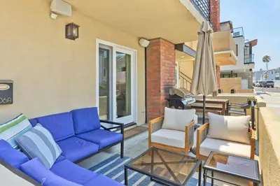 a patio with a blue couch and two chairs and an umbrella at Sail & Sea in Newport Beach