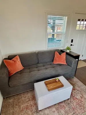 a living room with a gray couch with orange pillows at The Hilltop Haven - Romantic Getaway Suite in Temecula