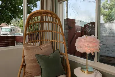 a rocking chair and a lamp in front of a window at Cozy Chic Casa ,Spa ,Ac ,Theatre , Downtown, Beach in La Mesa