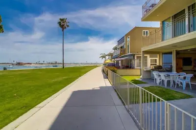 a walkway next to a building with a palm tree at Bayside Gem - Beachfront - Vibrant - Ocean Breeze in San Diego