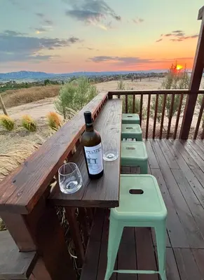 a bottle of wine sitting on a wooden bench on a deck at The Hilltop Haven - Private View Suite in Temecula