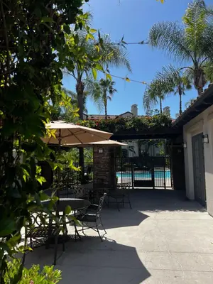 a patio with tables and chairs and an umbrella at Cozy Luxurious Spacious Apt with Valley View, Attached Garage,Pool,24-Hour Gym, 3 TV in Mission Viejo