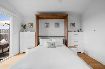 a bedroom with a large bed with white furniture at Bay View Bungalow in San Diego