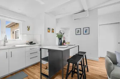 a kitchen with white cabinets and a counter with stools at Bay View Bungalow in San Diego