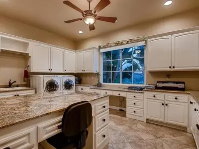 a large kitchen with white cabinets and a ceiling fan at La Bella Vista Estate in Fallbrook
