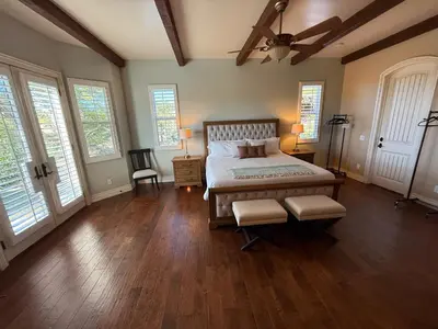 a bedroom with a large bed and wooden floors and windows at La Bella Vista Estate in Fallbrook
