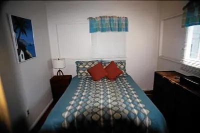 a bedroom with a bed with two red pillows at Mission Beach Cottage in San Diego