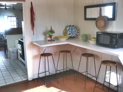 a kitchen with bar stools and a counter with a microwave at Mission Beach Cottage in San Diego