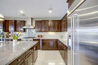 a kitchen with wooden cabinets and a stainless steel refrigerator at Daydream Palace in Chula Vista
