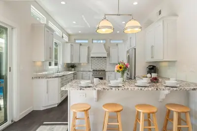 a kitchen with white cabinets and bar stools at Seaside Spiral in San Diego
