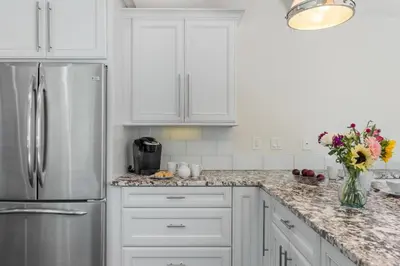 a kitchen with white cabinets and a stainless steel refrigerator at Seaside Spiral in San Diego