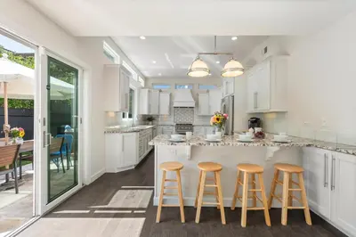 a kitchen with white cabinets and bar stools at Seaside Spiral in San Diego