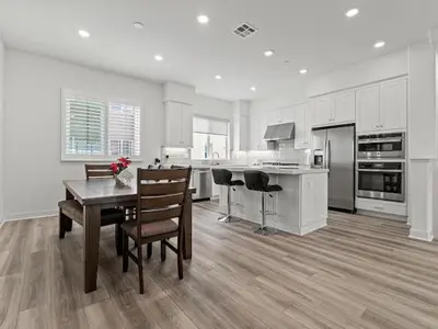a white kitchen with a wooden table and chairs at Beautiful Irvine Grand Park Community Cozy and Comfortable Home in Irvine
