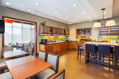 a large kitchen with wooden tables and chairs at Hyatt Place San Diego-Vista/Carlsbad in Vista