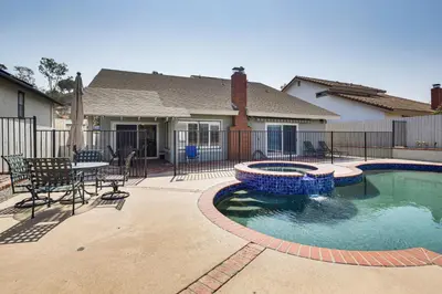 a swimming pool with a table and chairs in front of a house at Spacious Getaway with Pool and Spa in La Mesa! in La Mesa