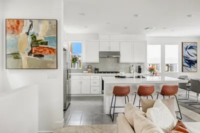 a kitchen and living room with white cabinets and a couch at Luxury Oasis Resort Pool&Spa Fitness Arcade in Ladera Ranch