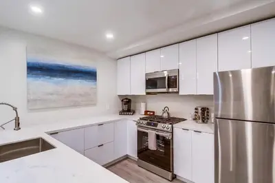 a kitchen with white cabinets and a stainless steel refrigerator at Lux Escape 1 • Views Hot Tub Games Mini Golf in San Diego