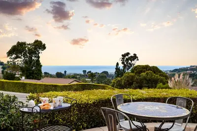 a table and chairs on a patio with a view of the ocean at Elegant La Jolla Villa - Ocean Views & Pool in San Diego