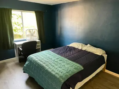a bedroom with a bed and a desk and a window at Sunny Condo Steps from Sand in San Diego