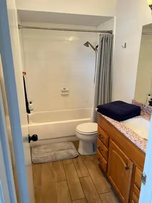 a bathroom with a tub and a toilet and a sink at Sunny Condo Steps from Sand in San Diego