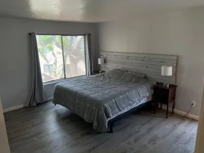 a bedroom with a bed and a large window at Sunny Condo Steps from Sand in San Diego