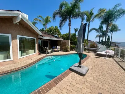 a swimming pool with an umbrella next to a house at San Diego Paradise - Scenic Views, Pool and Spa in El Cajon