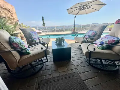 a patio with chairs and an umbrella and a pool at San Diego Paradise - Scenic Views, Pool and Spa in El Cajon