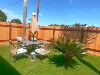 a table and chairs with a umbrella and a palm tree at Sea & Sun Getaway near Seaworld in San Diego