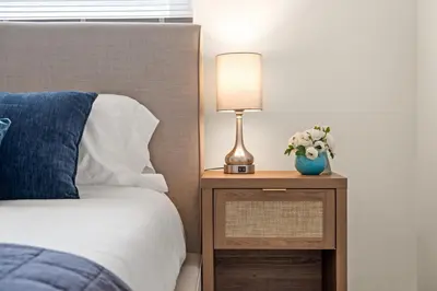 a bed with a nightstand with a lamp and flowers on it at Relaxing 3BR Getaway in Central SD in San Diego