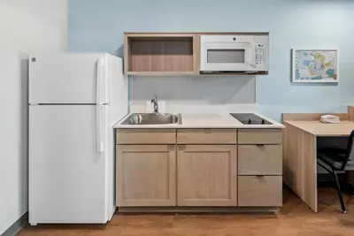 a kitchen with a white refrigerator and a sink at WoodSpring Suites Santee - San Diego Northeast in Santee