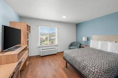 a bedroom with a bed and a flat screen tv at WoodSpring Suites Santee - San Diego Northeast in Santee