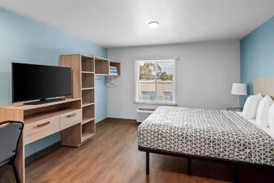 a bedroom with a bed and a flat screen tv at WoodSpring Suites Santee - San Diego Northeast in Santee