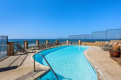 a swimming pool with chairs and the ocean in the background at Top of the Wave - DMST31 in Solana Beach