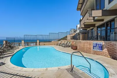 a swimming pool with chairs and a building at Top of the Wave - DMST31 in Solana Beach