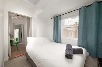 a bedroom with a white bed with blue curtains and a window at Centra Spacious Villa in San Diego