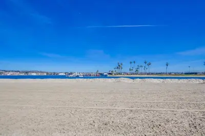a sandy beach with blue water and palm trees at Mission Bay Getaway - Walk to the Water in San Diego