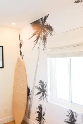 a room with a surfboard and palm trees on the wall at The Swell Oceanview Designer Stay Hot Tub in Oceanside