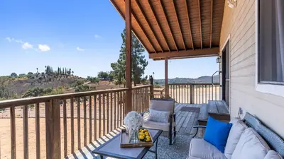 a patio with a couch and chairs on a balcony at Scenic Deck w Sunset Views Near Temecula Wineries Estrada Ranch by AvantStay in Fallbrook