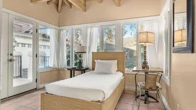 a bedroom with a bed and a desk and windows at Two Estates w Pools Hot Tubs Game Rooms Valley Views Tennis Court Near Beaches Wineries in Escondido