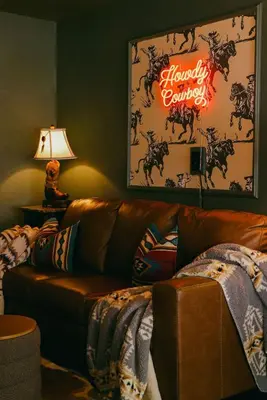 a living room with a brown leather couch and a neon sign at Wild Moon Ranch with Pickleball, Cedar Tub, Views in Julian