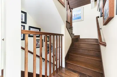 a staircase with wood treads and white walls at Luxury 4Br Beachfront Home W Panoramic Ocean Views By Beachview Rentals in Newport Beach