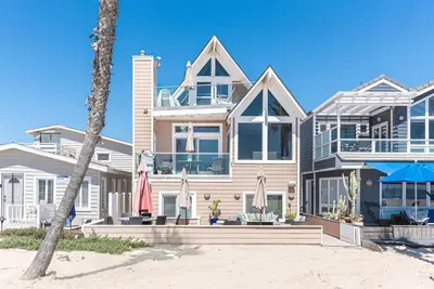 a house on the beach with a palm tree at Luxury 4Br Beachfront Home W Panoramic Ocean Views By Beachview Rentals in Newport Beach