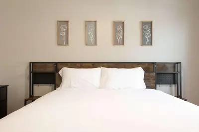 a bedroom with a white bed with four pictures on the wall at Cozy Pet Friendly Escape with Outdoor Dining in San Diego
