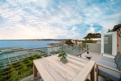 a wooden table on a balcony with a view of the water at Terrace Views at La Jolla Cove in San Diego