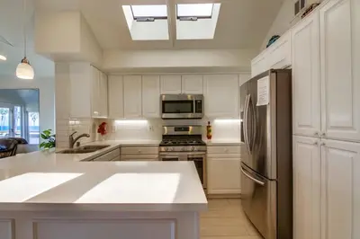 a kitchen with white cabinets and a stainless steel refrigerator at Stunning beach home located between bay and beach with Ocean View Patio in San Diego