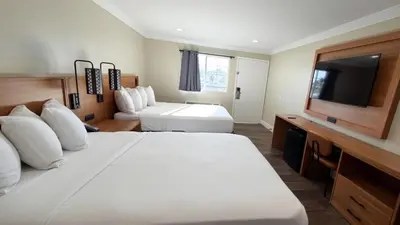a hotel room with a bed and a flat screen tv at Border Plaza Hotel in San Diego