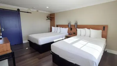 a hotel room with two beds and a blue door at Border Plaza Hotel in San Diego