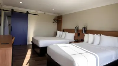 a hotel room with two beds and a blue door at Border Plaza Hotel in San Diego