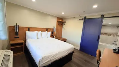a bedroom with a large bed and a blue door at Border Plaza Hotel in San Diego