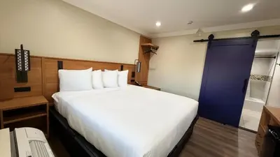 a bedroom with a large white bed and a blue door at Border Plaza Hotel in San Diego